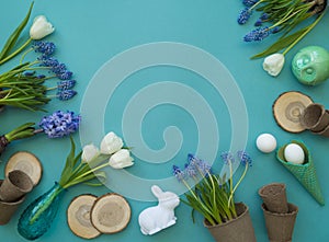 Easter decorative composition on a blue background. White tulips, flower pots, unpainted eggs and a tree.