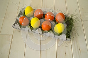 Easter. Easter eggs are yellow and orange. Eggs lie in the container for eggs. Green grass.