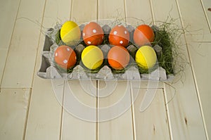 Easter. Easter eggs are yellow and orange. Eggs lie in the container for eggs. Green grass.