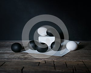 Easter. Easter night. Black and White eggs, feathers on a wooden table. Vintage. Dark background.