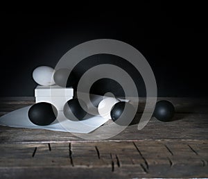 Easter. Easter night. Black and White eggs, feathers on a wooden table. Vintage. Dark background