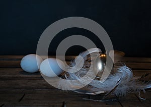 Easter. Easter night. Golden and White eggs, feathers on a wooden table. Vintage. Dark background