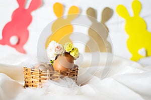 Easter egg in a basket. Easter egg decorated with yellow roses wreath and paper bunnies