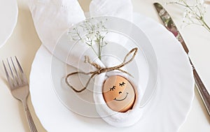 Easter egg with a cute face in a plate with bunny ears, as happy Easter concept