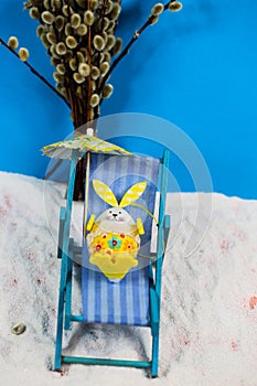 Easter egg in deck chair, blue background, holiday on easter