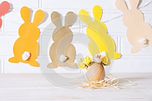 Easter egg decoration. Easter egg decorated with yellow roses wreath and paper bunnies