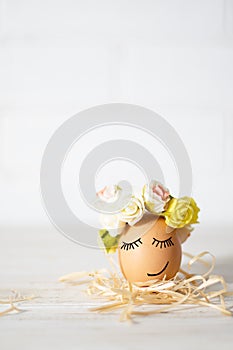 Easter egg with funny face. Funny easter egg decorated yellow roses wreath