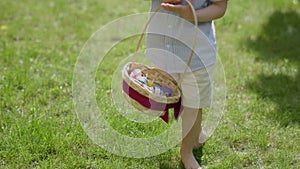 Easter egg hunt: barefoot child searching colourful Easter eggs hidden in grass