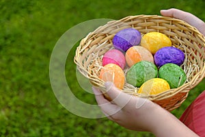 Easter Egg Hunt. Easter eggs set in a basket in children& x27;s hands on green grass background. Collecting eggs. Religious