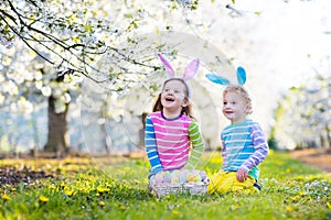 Easter egg hunt. Kids with bunny ears in spring garden.