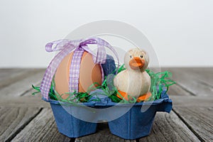 Easter egg with a ribbon and a little duck in a carton