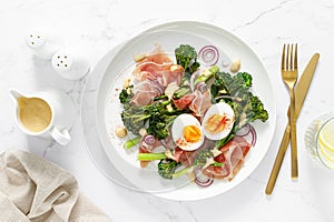 Easter egg salad with prosciutto and broccolini on white background, top view. Easter salad with boiled egg
