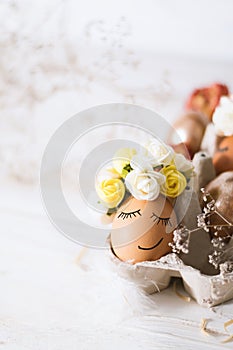 Easter egg with smiling face. Funny easter egg decorated yellow roses wreath. Easter egg is sleeping