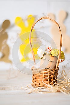 Easter egg with smiling face. Funny easter egg decorated yellow roses wreath and paper bunnies. Easter egg is sleeping