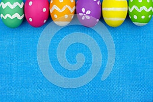 Easter egg top border over blue burlap background