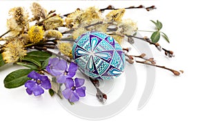 Easter egg, twigs of flowering willow and flowers of periwinkle on a white background