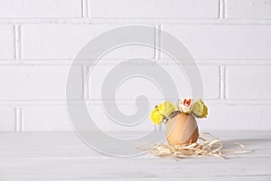 Easter egg on a white desk. Funny easter egg decorated yellow roses wreath. Copy space