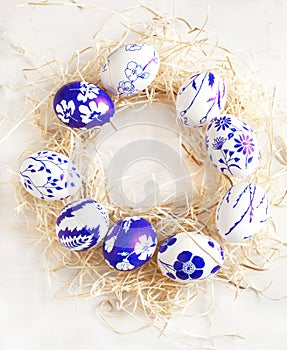 Easter egg wreath on a white wooden background.