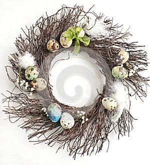 Easter egg wreath on a white wooden background.