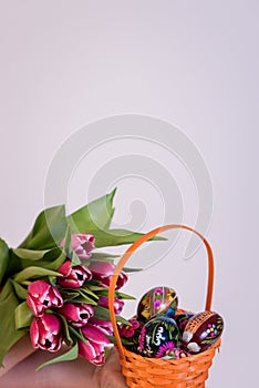 Easter eggs in basket and colorful tulips in hand