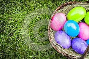 Easter eggs in a basket on green grass with copy space