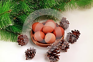 Easter Eggs in a Basket with Several Pinecones and green spruce on white background