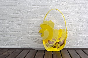 Easter eggs in basket on shelf in front of wooden wall. View with copy space
