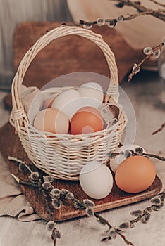 Easter eggs in basket and willow branches on rustic background