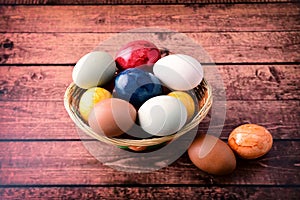 Easter eggs in basket, on wooden background.