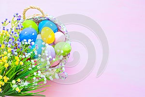 Easter eggs in basket on wooden pink table. Top view