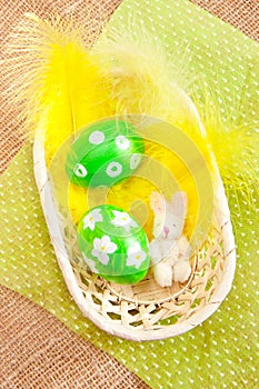 Easter eggs in a basket with yellow feathers