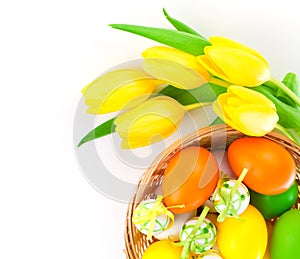 Easter eggs in a basket with yellow tulips flowers