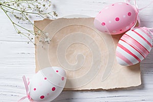 Easter eggs and blank note on wooden background, pastel colors, top view