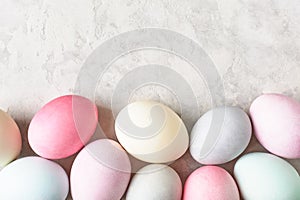 Easter eggs border on light grey background, colorful pastel dyed.