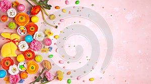 Easter eggs Bunny candy and colorful spring flowers on pastel pink background