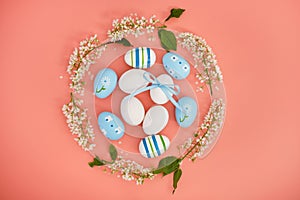 Easter eggs and cherry branches in the shape of a circle on a pink background. Copy space. Easter background, top view.