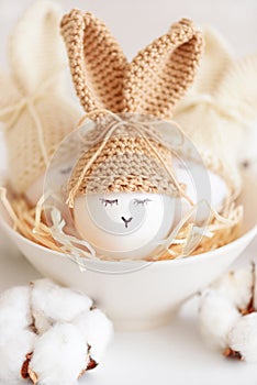 Easter eggs in crochet knitted hats with rabbit ears in nest. Easter celebration concept