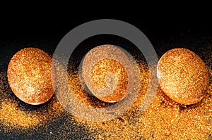 Easter eggs decorated with golden spangles on black background. Festive concept, minimalism. Close-up