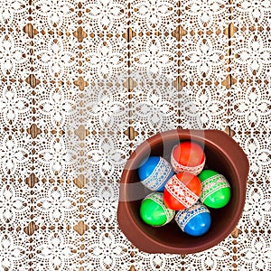 Easter eggs decorated with lace in a bowl on white crochet tablecloth