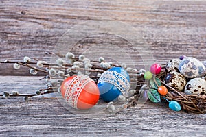 Easter eggs decorated with lace, pussy-willow and quail eggs in small nest on wooden background