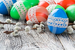 Easter eggs decorated with lace and willow branch on wooden background. Selective focus