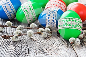 Easter eggs decorated with lace and willow branch on wooden background. Selective focus, copy space