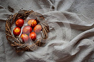 Easter Eggs Decorated with Natural Fresh Leaves and Boiled in Onions Peels on gray linen tablecloth in a wreath. Happy Easter conc