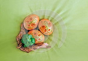 Easter eggs decorated with poppy flowers and a branch and plant on velvet, olive, green canvas background, top view.