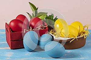 Easter eggs of different colors in a basket and pots with straw
