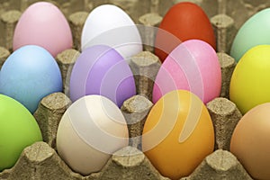 Easter eggs of different colors in a cardboard egg tray