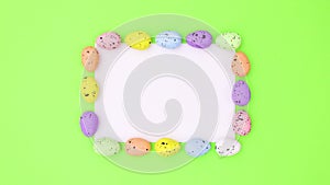 Easter eggs different colors move around paper for text on green theme. Stop motion