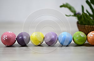 Easter eggs on Easter day background with colorful Eastereggs lined up, rattan basket decoration on white wooden table background.