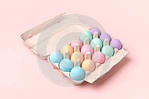 Easter eggs in egg box on pink background, pastel colors, minimal style.