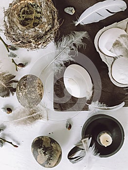 Easter eggs, feathers, pussy willow, candle, nest on rustic table. Easter flat lay, still life